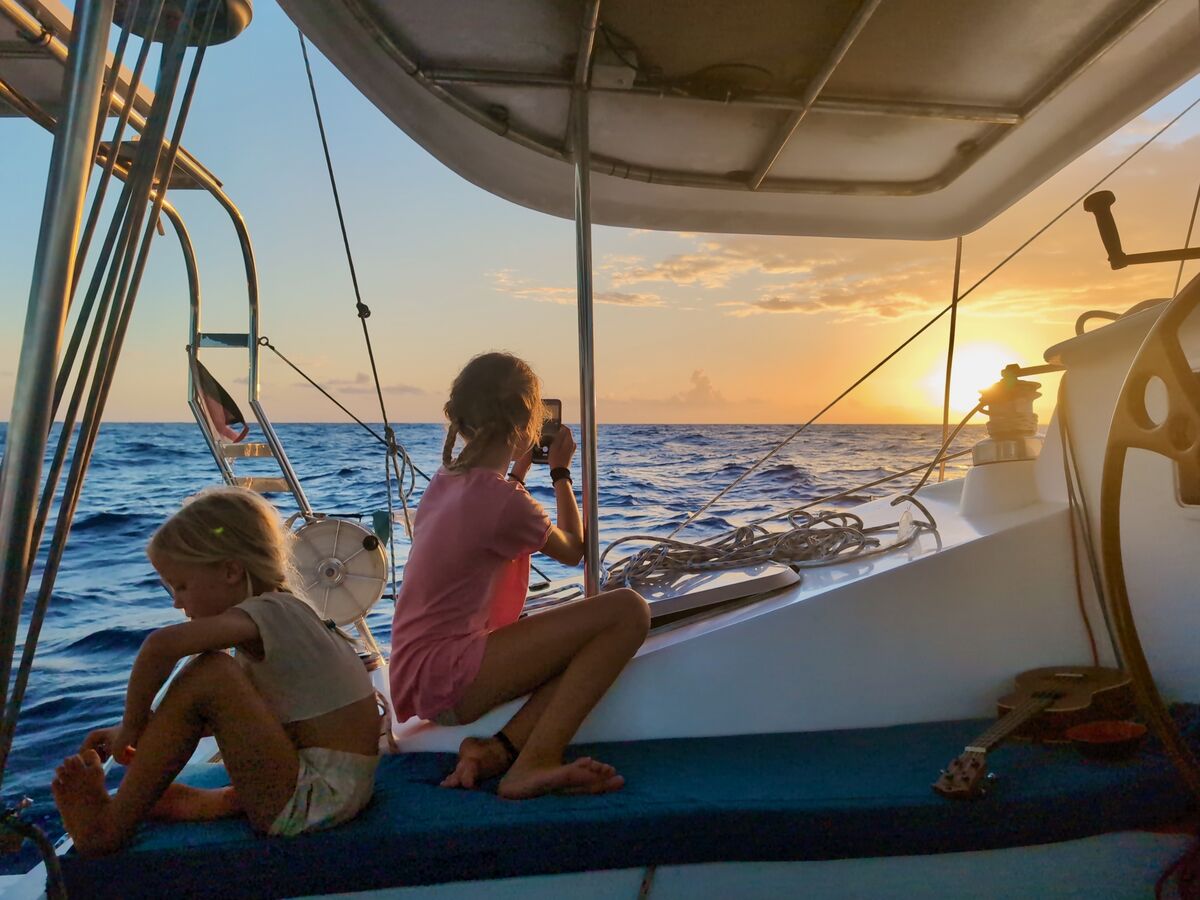 Children on deck under the hardtop at sunset on passage