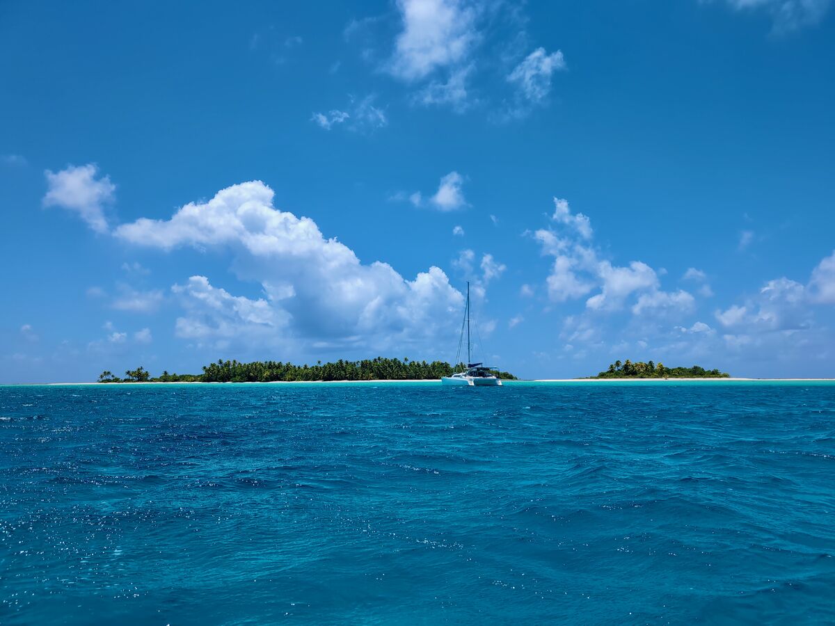 Zoë anchored off a palm motu in a brilliant blue lagoon