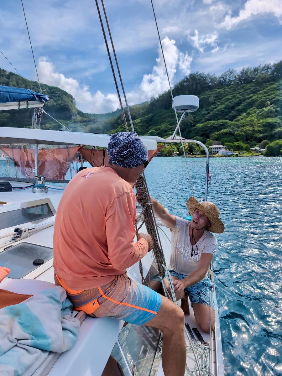 Working the foredeck rigging at anchor below green hills